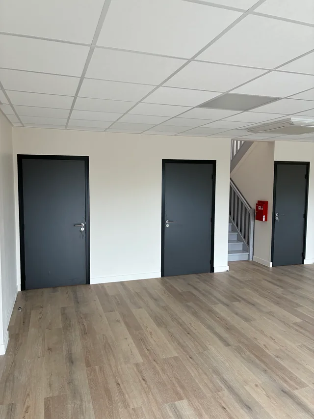 Cloisons et portes grises desservant les espaces intérieurs à proximité d’un escalier.